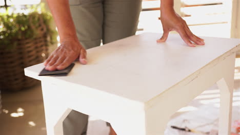 sanding wooden table, person refinishing furniture for home improvement project