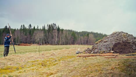 a man is setting charred stakes into the ground to mark the field - static shot