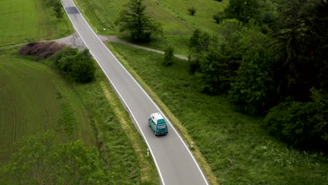 aerial: old camper van driving through european landscape on roadtrip