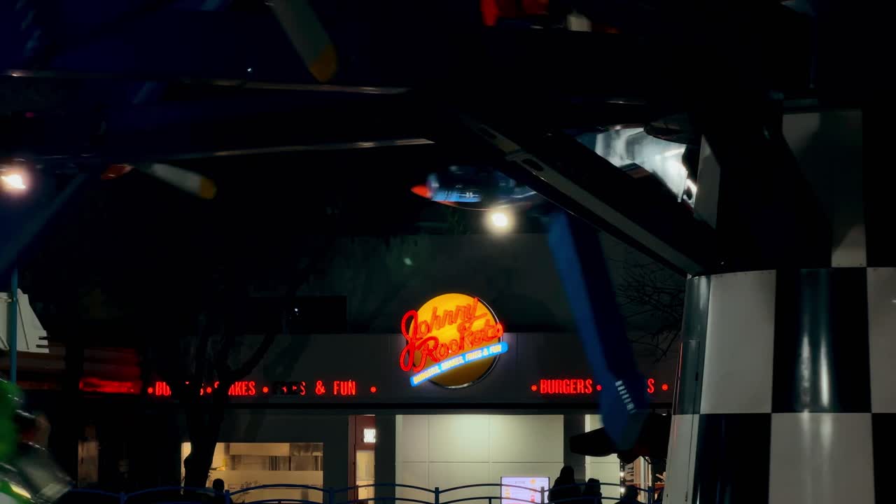 Establishing with the isolated Johnny Rockets sign illuminated at night, at the Fantasilandia amusement park in Santiago, Chile.