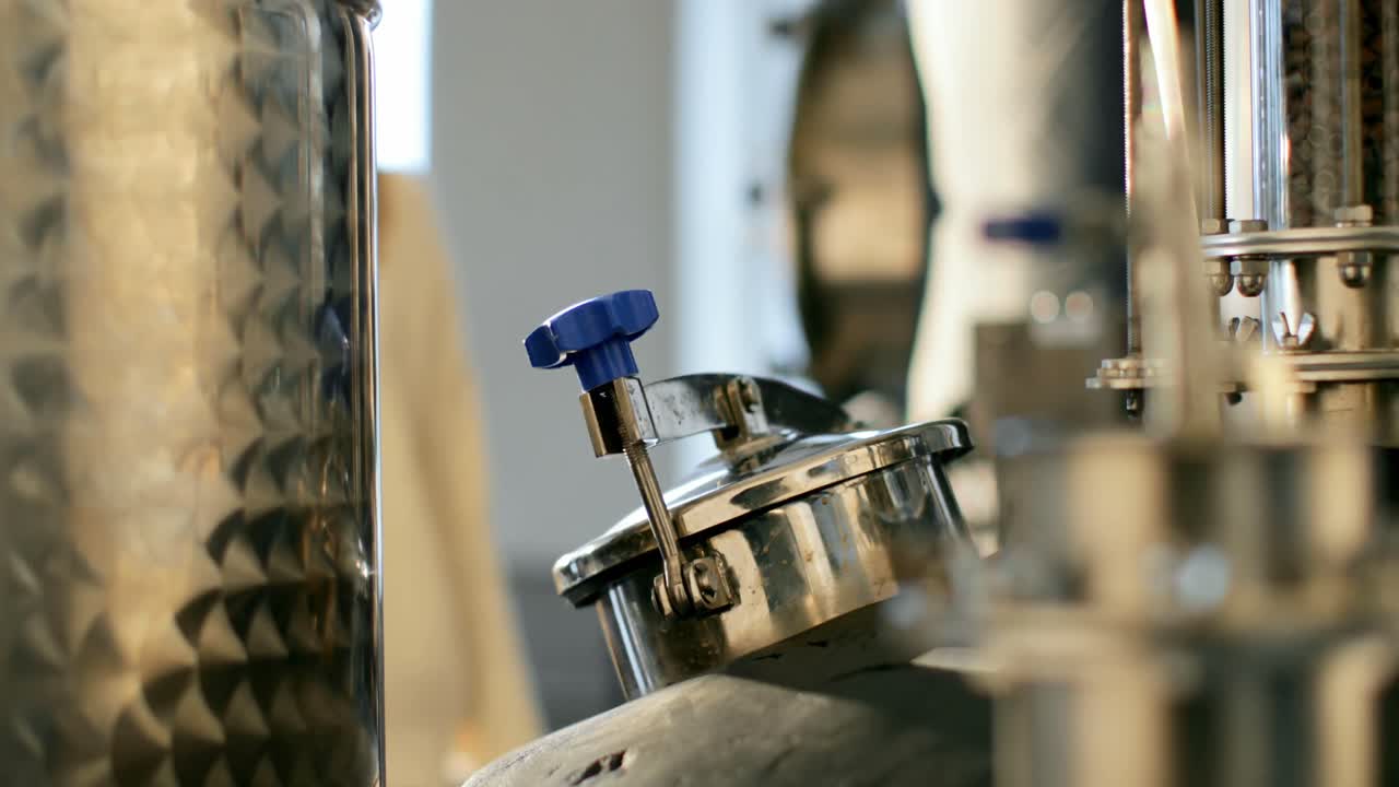 trabajadora que abre una válvula en una destilería 4k