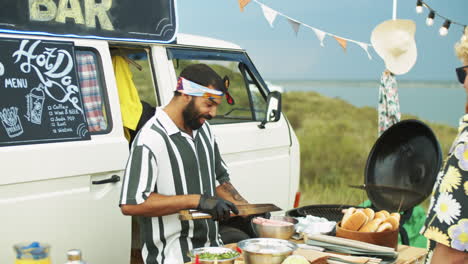 cheerful seller cooking hot dogs for customer at food truck