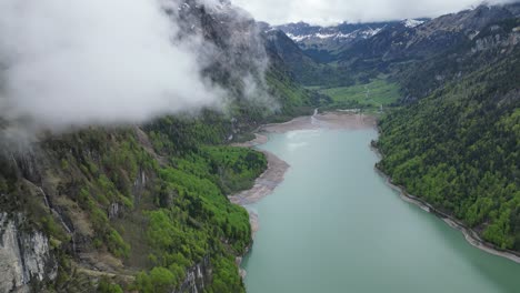 Stunning-aerial-view-of-clouds-descending-at-serene-Klontalersee-lake