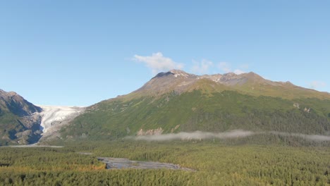a slowly horizontal moving aerial view of exit glacier in kenai fjords national park during fall, featuring a river, the majestic mountains, and the glacier itself. captured near seward, alaska