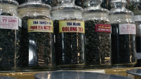 Assorted-tea-jars-on-shelves-at-Ben-Thanh-market-in-Saigon,-displaying-variety