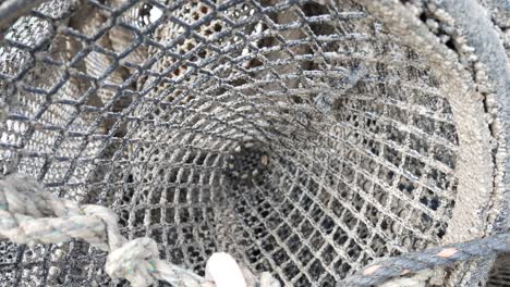 close up inside fishing harbour group of stacked lobster pots on coastal marine waterfront pull away