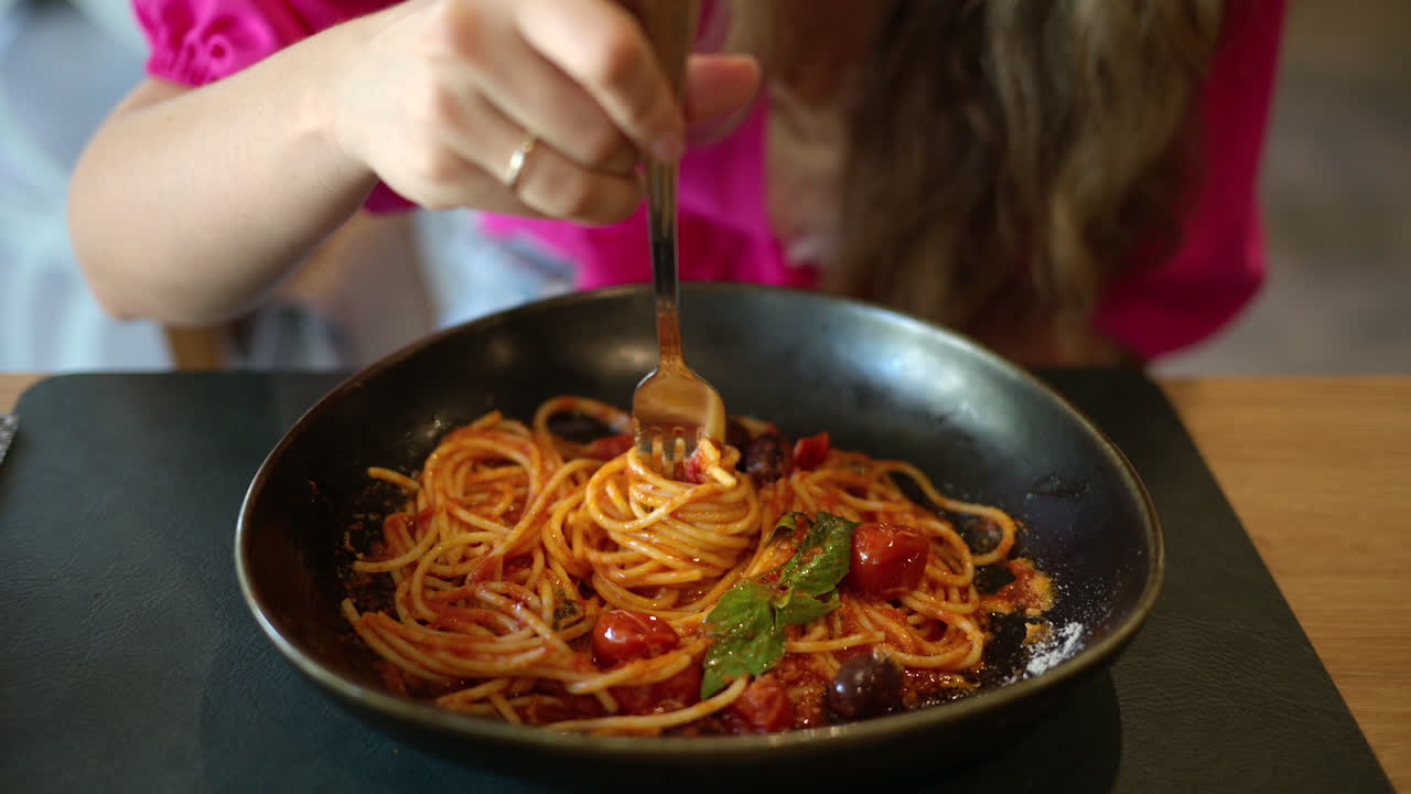 Woman eating italian spaghetti with tomatoe and basilic in a restaurant
