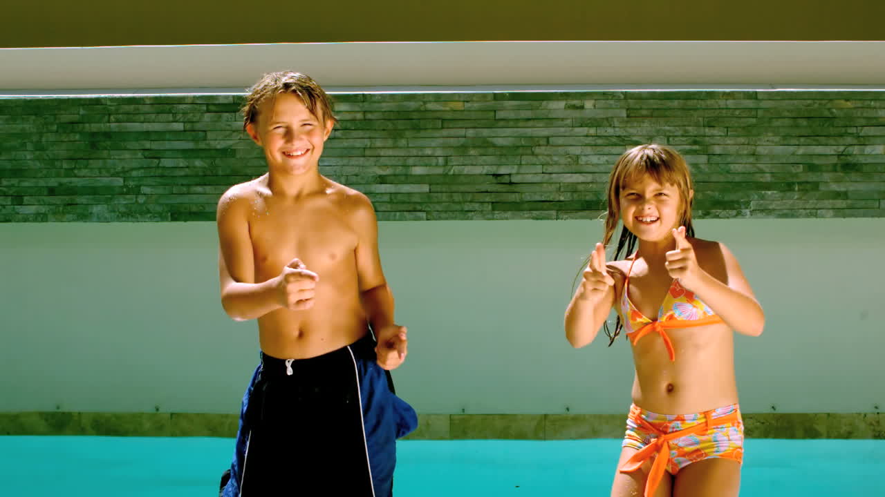 hermanos bailando juntos frente a la piscina