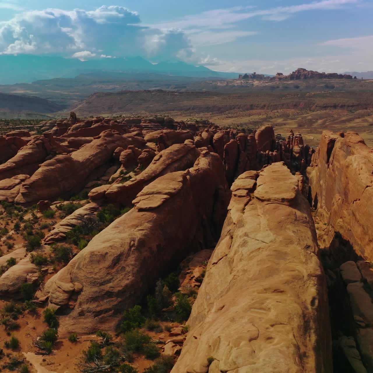 Long rocky apexes of Arches National Park in Utah, USA. Beautiful sunny landscape. Cloudscape over the mount at backdrop