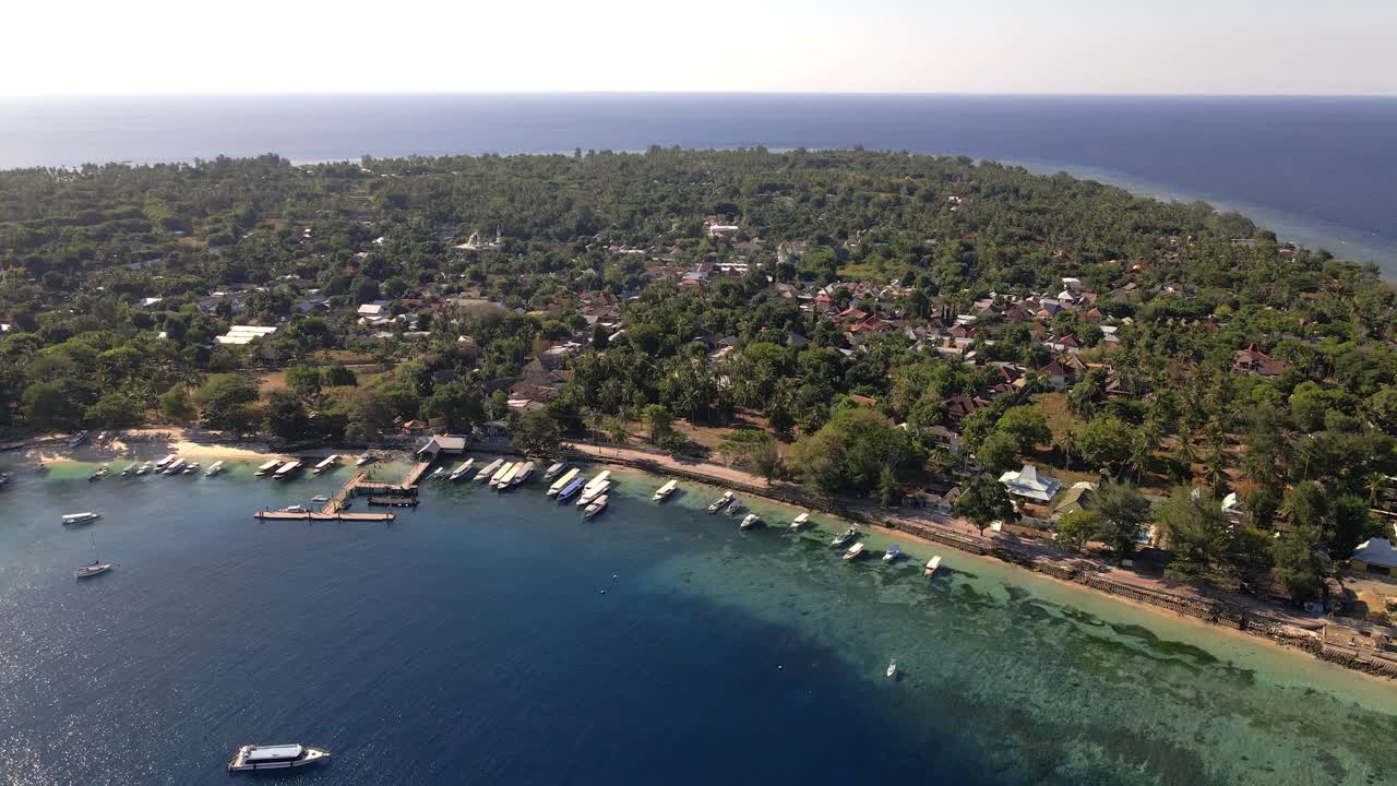 imágenes aéreas hacia atrás de la hermosa isla de gili air con árboles, costas oceánicas, barcos y hoteles durante el día soleado