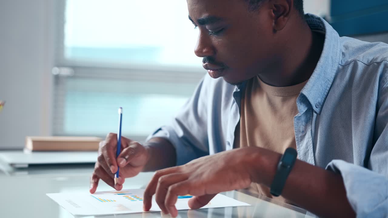 Serious young american businessman checking corporate paperwork at office desk