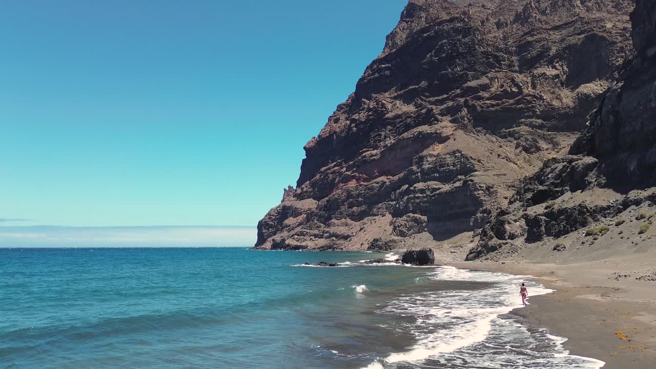 escena idílica de una mujer relajándose relajándose en una playa virgen virgen en gran canaria, españa durante el verano en vacaciones