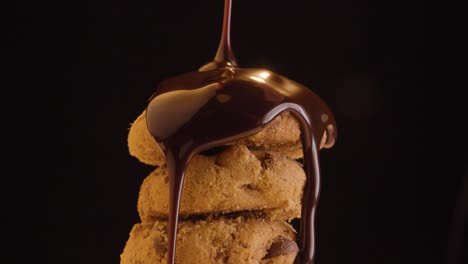 static shot and close up of delicious vegan cookies doused with vegan chocolate against a black background