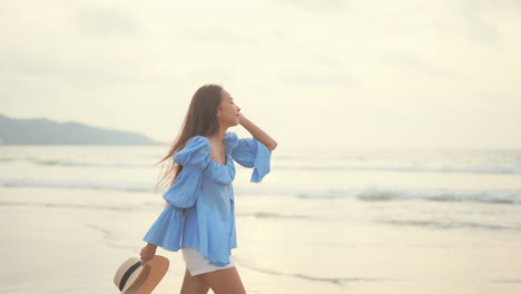 석양에 섬 해변 라인을 따라 걷는 아름다운 아시아 여자