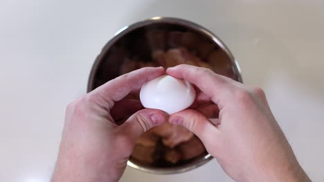 cracking a egg over raw chicken, cooking fresh food