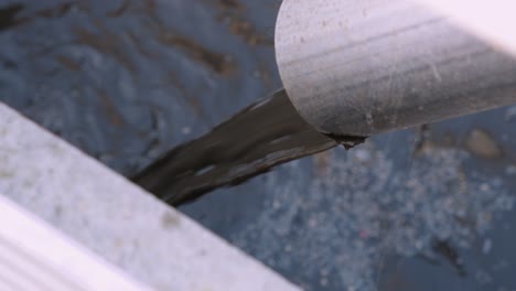 detailed view of wastewater exiting a pipe in a treatment plant, symbolizing environmental pollution and the need for clean water management, dominant blue-gray color.