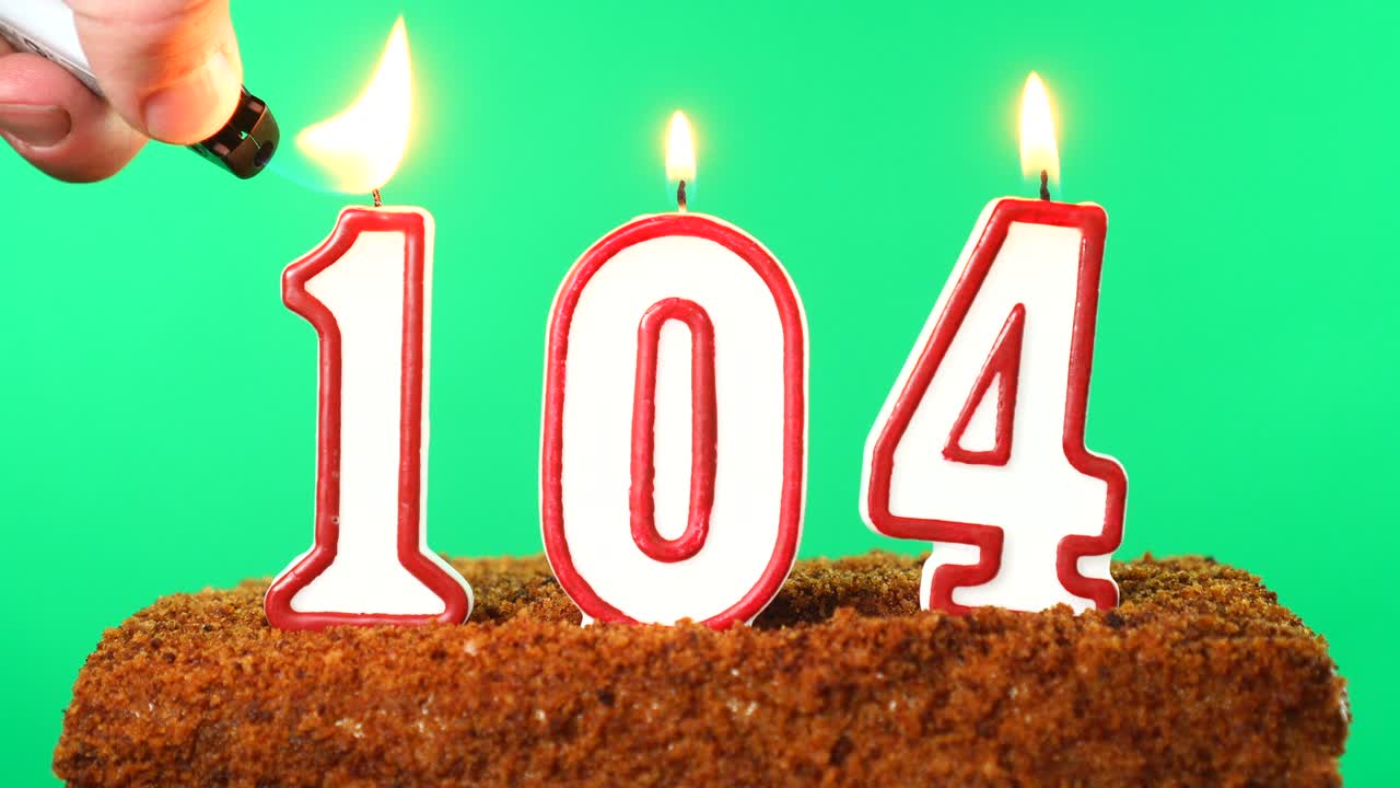 торт с номером 104 зажженной свечой. ключ хромы. зеленый экран. изолирован