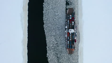 top down aerial view of two car ferries passing each other as they cross an ice covered river