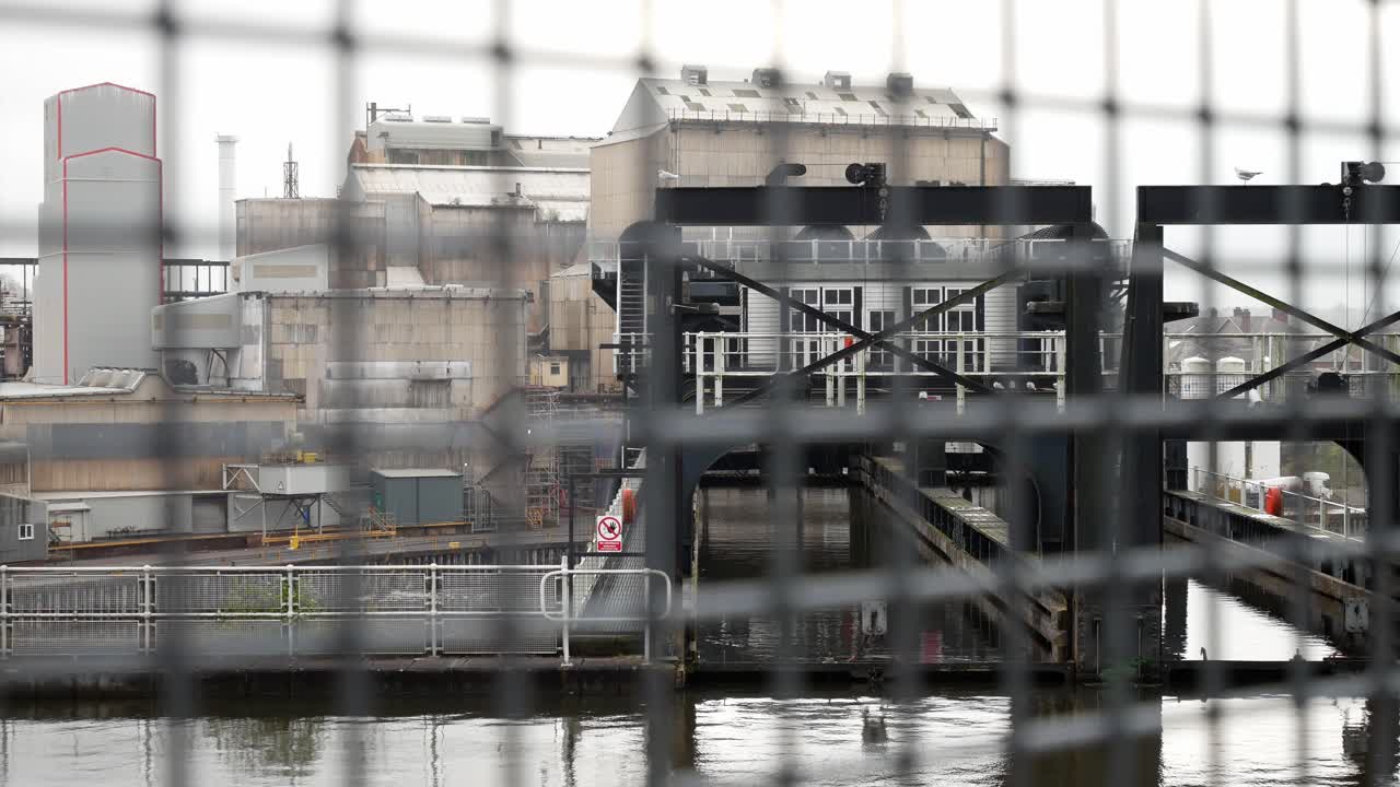 Portail de sécurité silencieux et vide, clôture en treillis métallique, canal, entrepôt industriel, chariot à gauche.