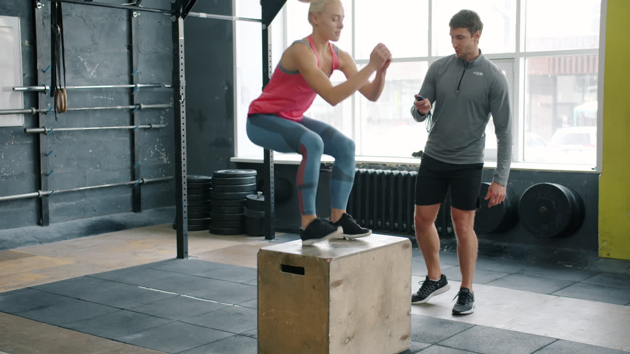 Woman Doing Box Jumps and Squats with a Personal Trainer