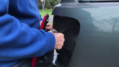 man attempts to detach the tail light assembly replacement of rear lights from the car - close up