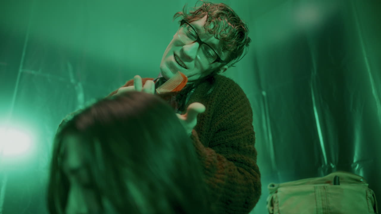 un maníaco psicótico cepillando el cabello de una chica asustada sentada atada con la boca pegada