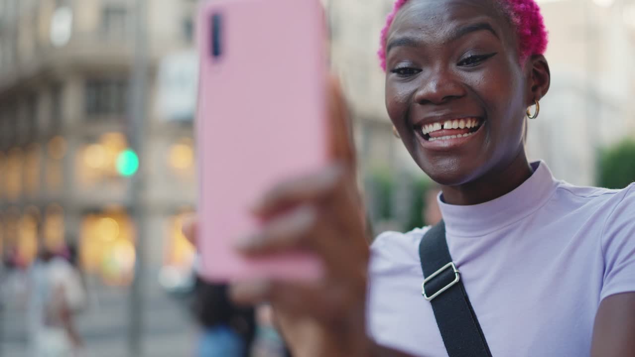 Young woman with pink hair video calling or taking a selfie in the city