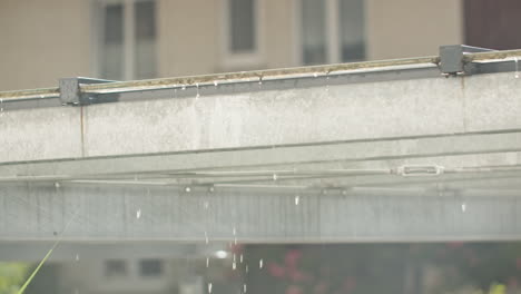 medium close up shot of a metal beam with rain drops dropping in slow motion after storm