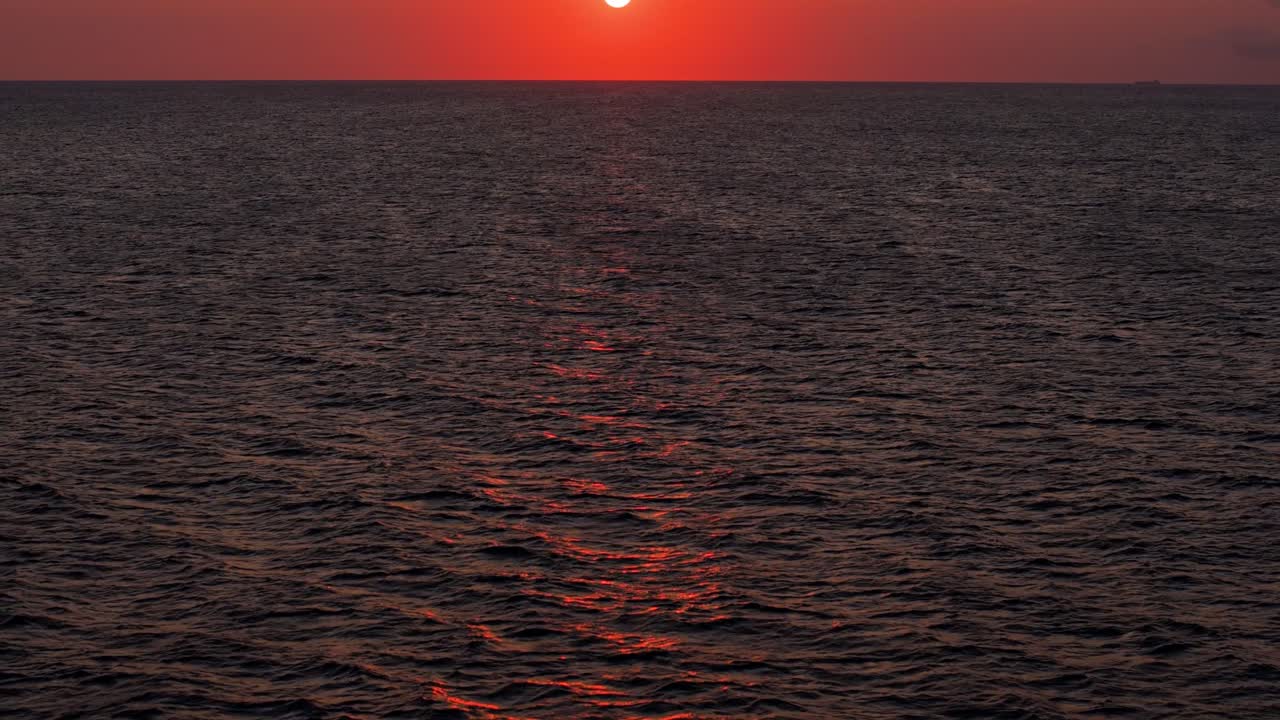 공중으로 끌어올리며 어보면 아름다운 불빛, 은 오렌지색, 평온한 바다 물 위에서 해가 지는 모습이 보인다.