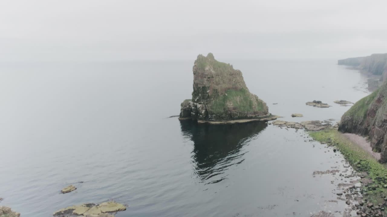 Slow drone reveal of the Stacks of Duncansby in misty weather along the Scotland North Coast 500 route at John O'Groats