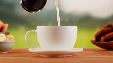 pouring milk into a hot cup of coffee or tea with cookies