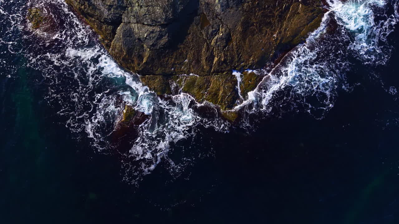Waves crashing against rocky shoreline at sunset create a stunning panorama of nature's power and beauty