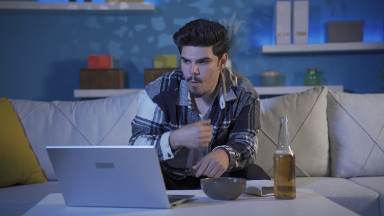 Young man watching movie on laptop. He's focused on the movie.