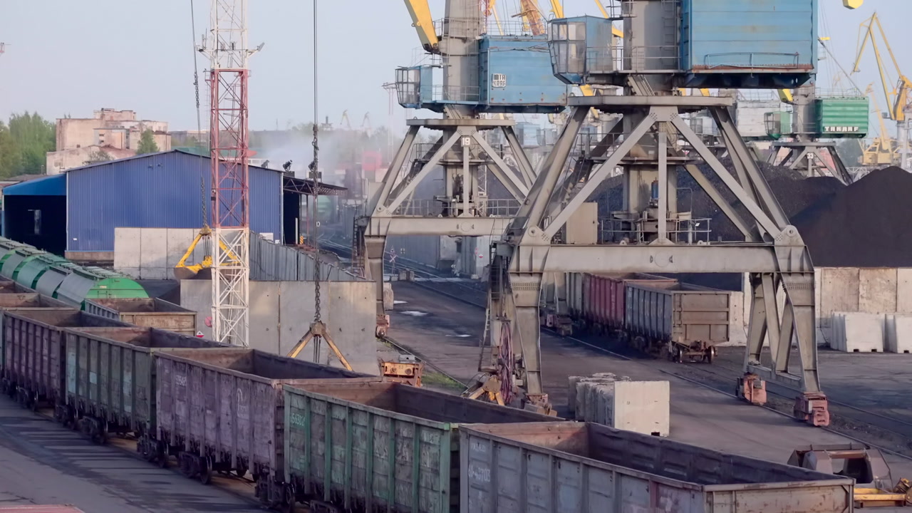 Industrial Port Cranes Loading Coal Wagons, Giant Gantry Structures Transferring Bulk Coal Into Long Line. Creative