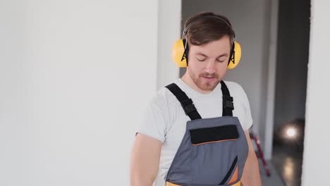 repairman puts on headphones and takes a drill in his hand