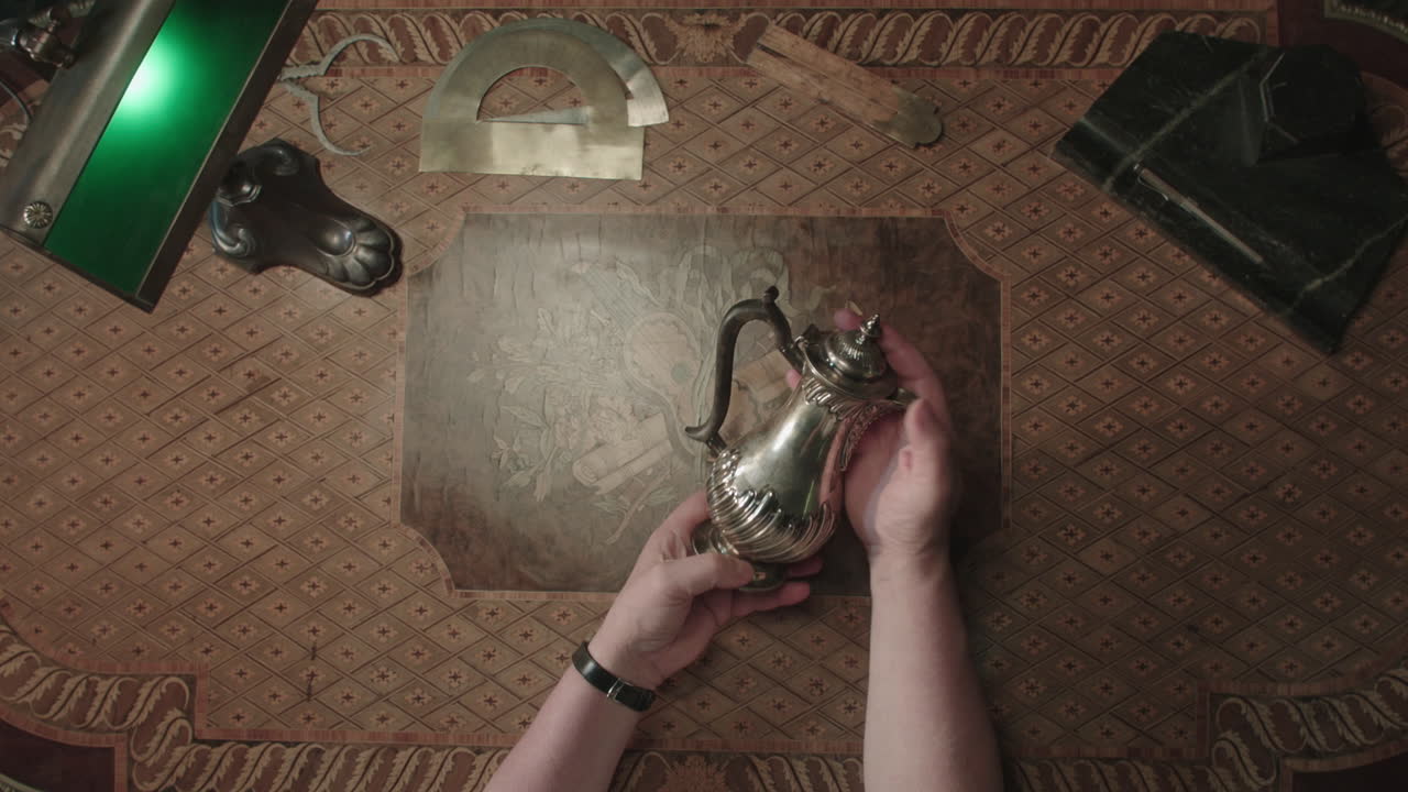 An older man evaluates an antique pitcher