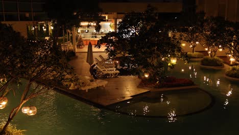 nighttime view of a lit garden by a pool