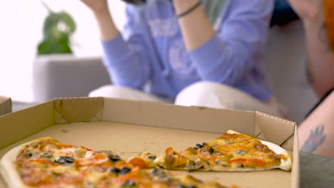 close up of a young woman eating pizza with friends at home