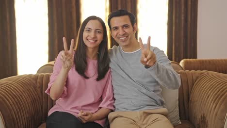 una feliz pareja india mostrando el signo de la victoria