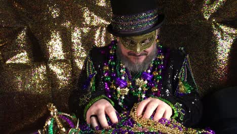 happy mardi gras man in fancy costume with top hat holding pile of beads