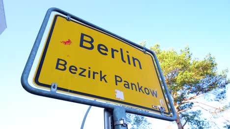 close up of yellow berlin city sign under blue sky in pankow district