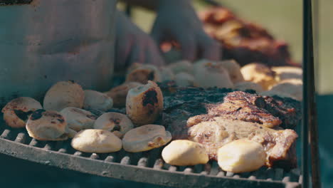 grilled meat asado and chipa, traditional argentine food with burning and smoking firewood, close up