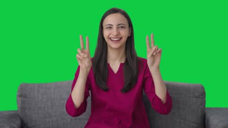 mujer india feliz mostrando el signo de la victoria pantalla verde