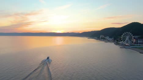 puesta de sol sobre un lago con un barco y una ciudad en el fondo