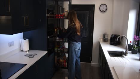 Modelo-Femenino-Tomando-Un-Frasco,-Comida-De-Una-Despensa-Extraíble-En-Una-Cocina-Moderna