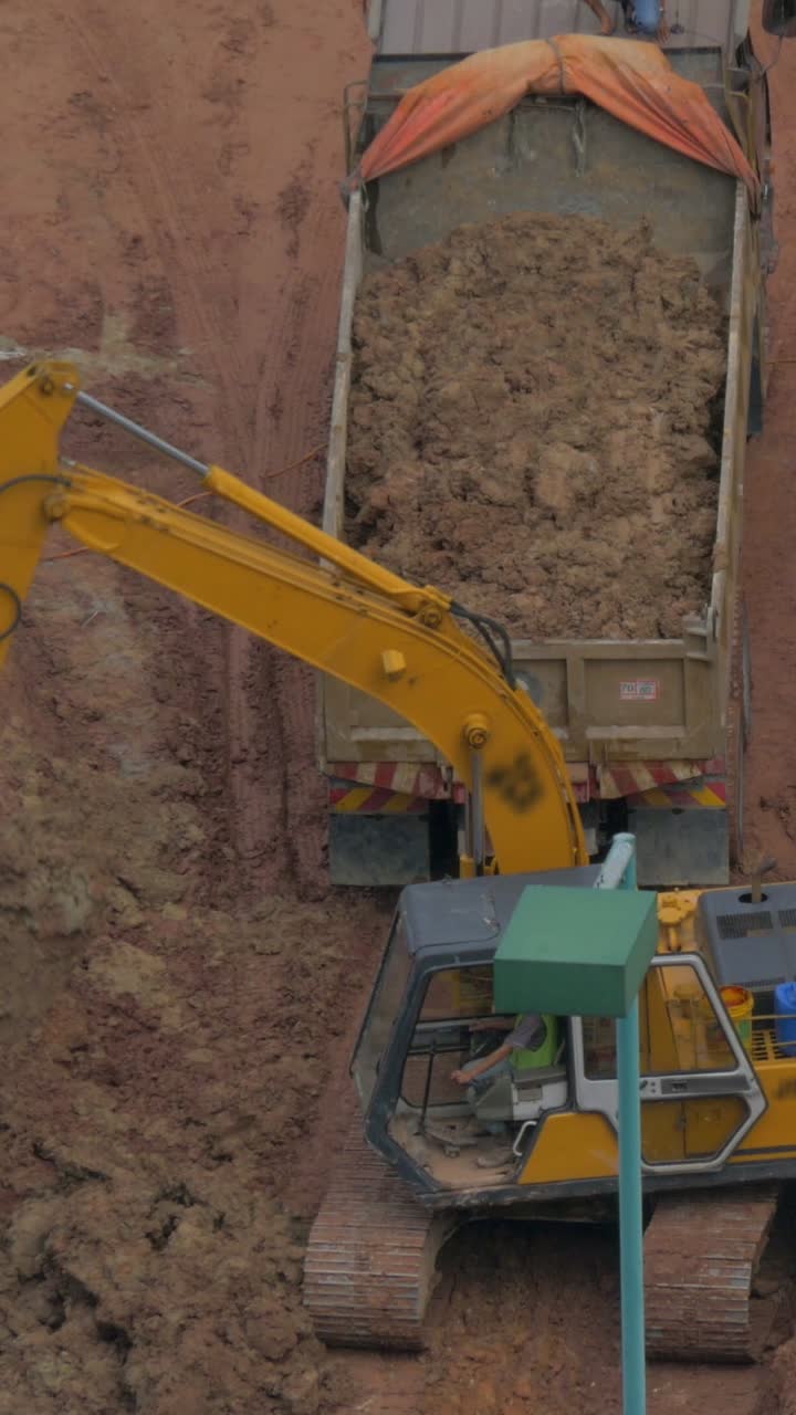 Excavadora excavando y cargando tierra en un camión volquete en una obra
