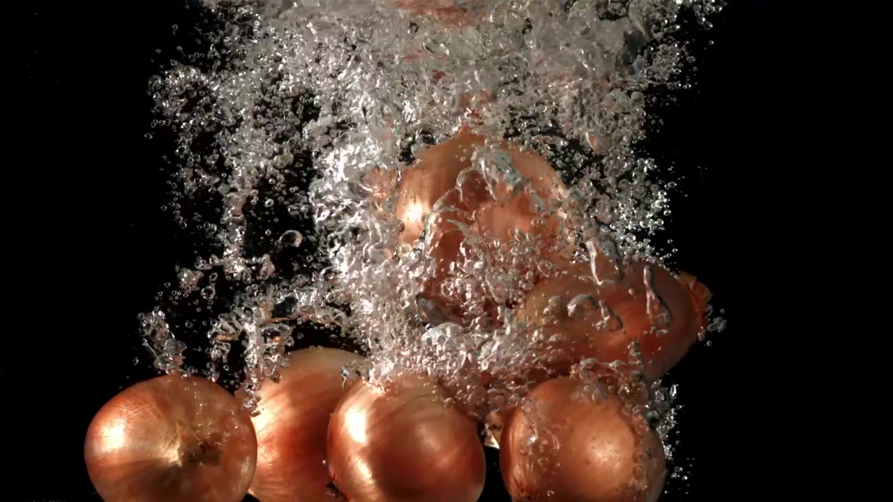 Cipolle fresche che schizzano nell'acqua al rallentatore