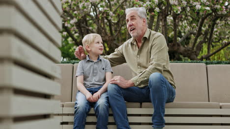 grandfather and grandson sitting on a bench in the park