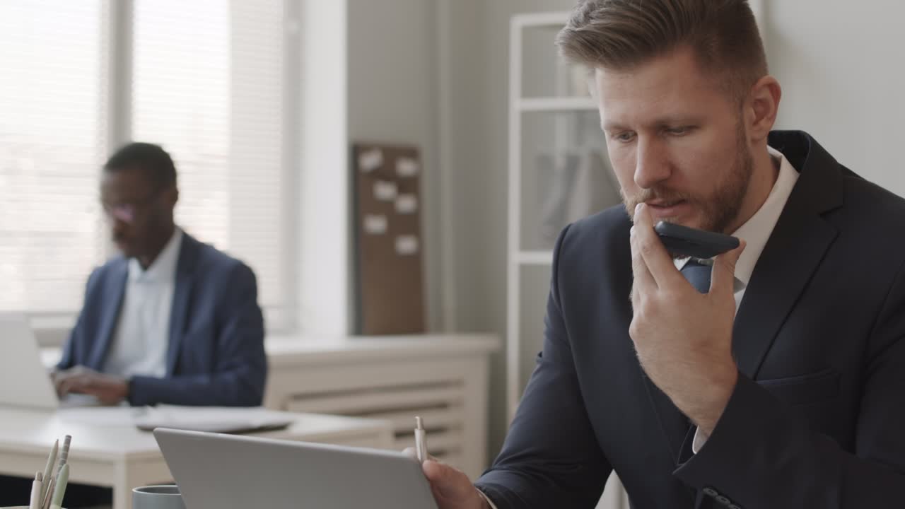Broker uomo che parla in vivavoce in ufficio.