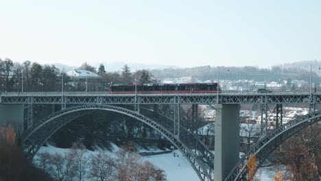 red tram passing over a bridge and a sunny winter day in bern, switzerland